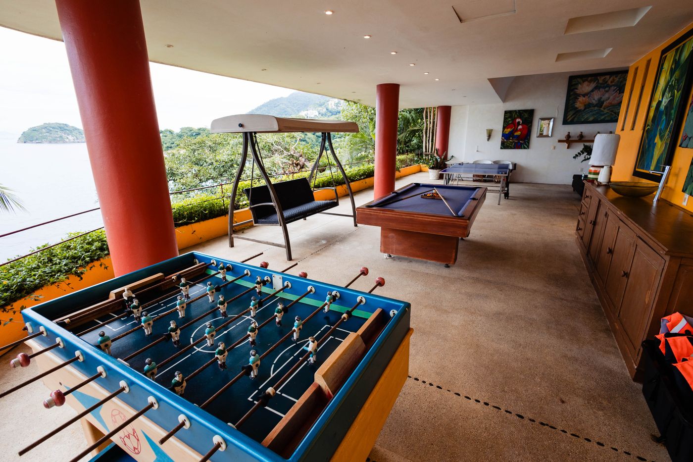 Covered terrace with a foosball table and a pool table and a view of the ocean