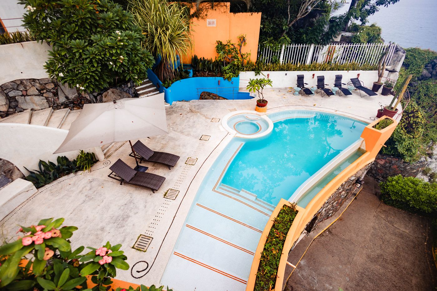 Aerial view of a pool with steps, a round hot tub and loungers on a terrace at Villa Mandarinas