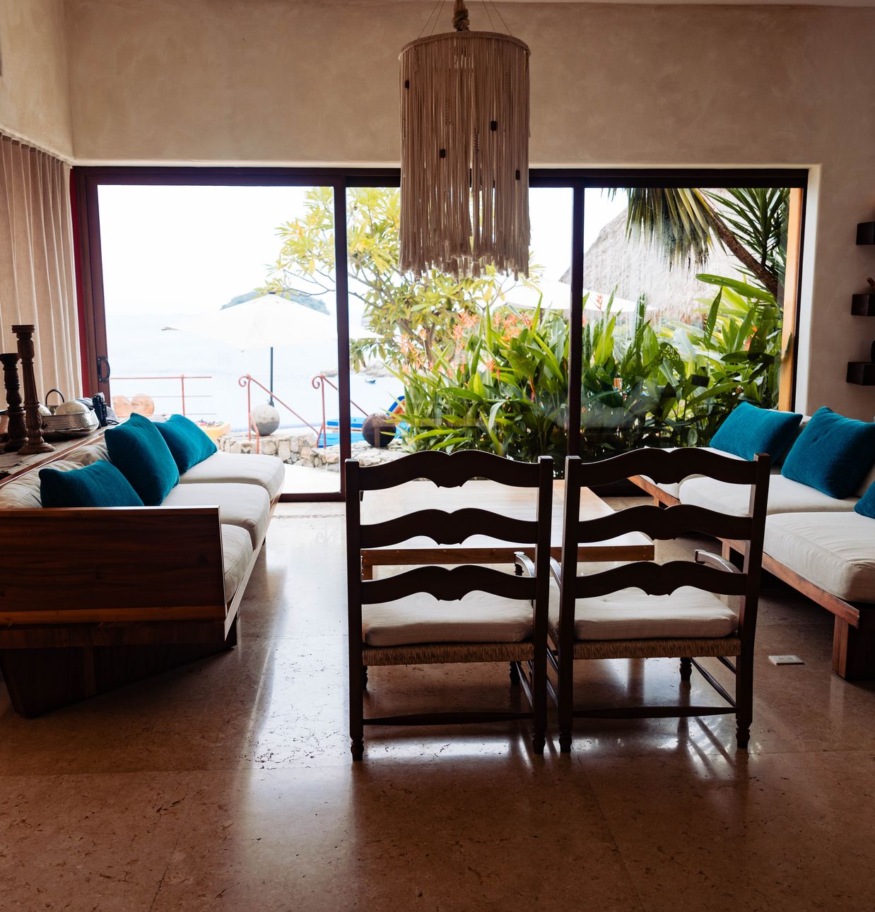 Living room with blue and white sofas, a wooden bar area and large windows onto the garden