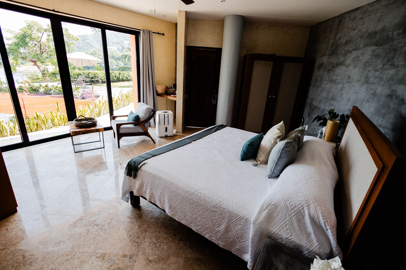 Bedroom with a king bed, concrete accent wall and floor-to-ceiling windows at Villa Mandarinas
