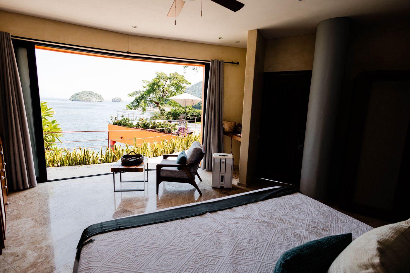 Bedroom with a bed facing a wide window that looks out to the ocean at Villa Mandarinas