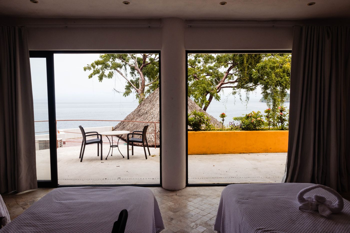 Bedroom with two beds opening onto a terrace with an ocean view at Villa Mandarinas
