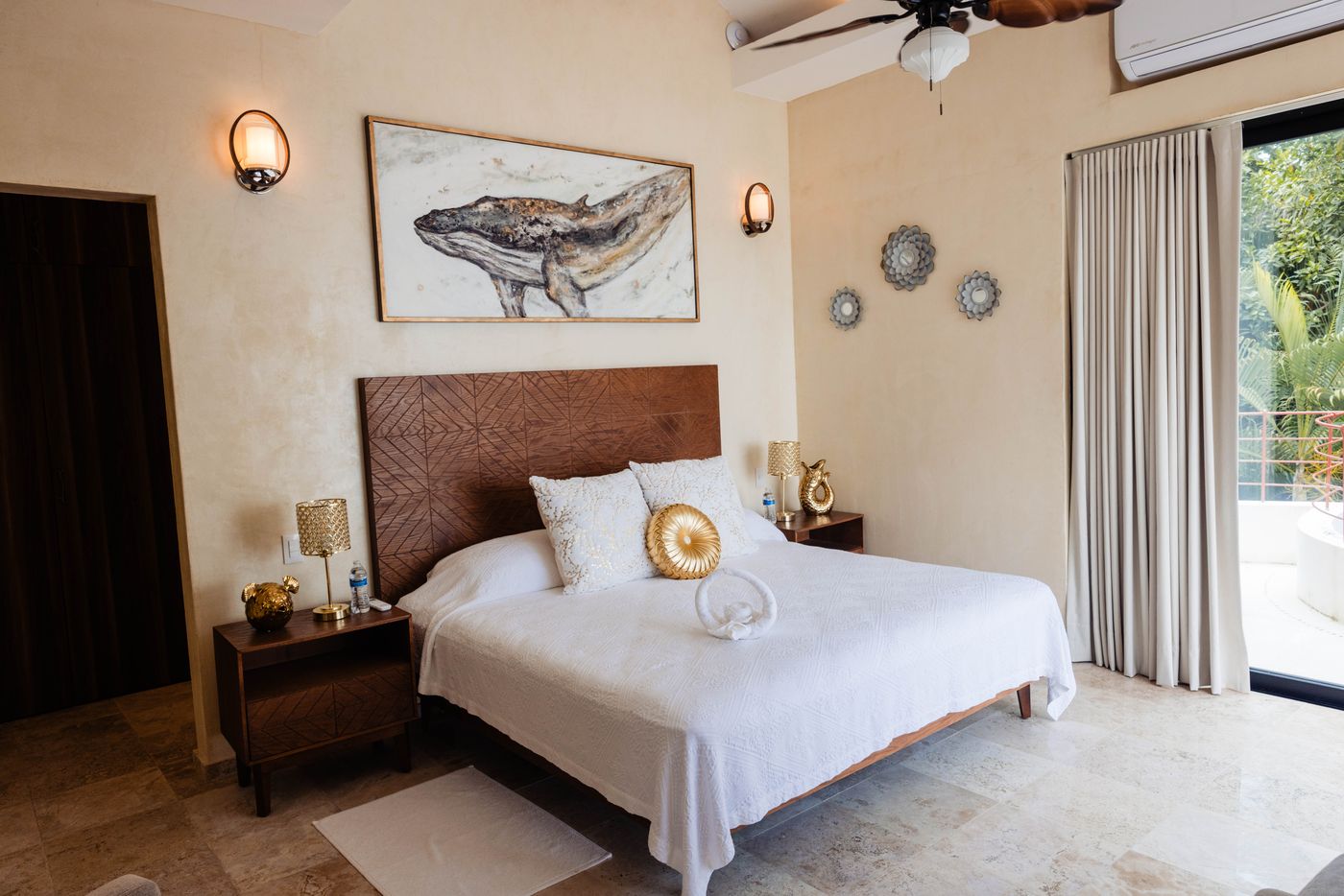 Bedroom with a king bed, wood headboard and whale artwork on the wall at Villa Mandarinas