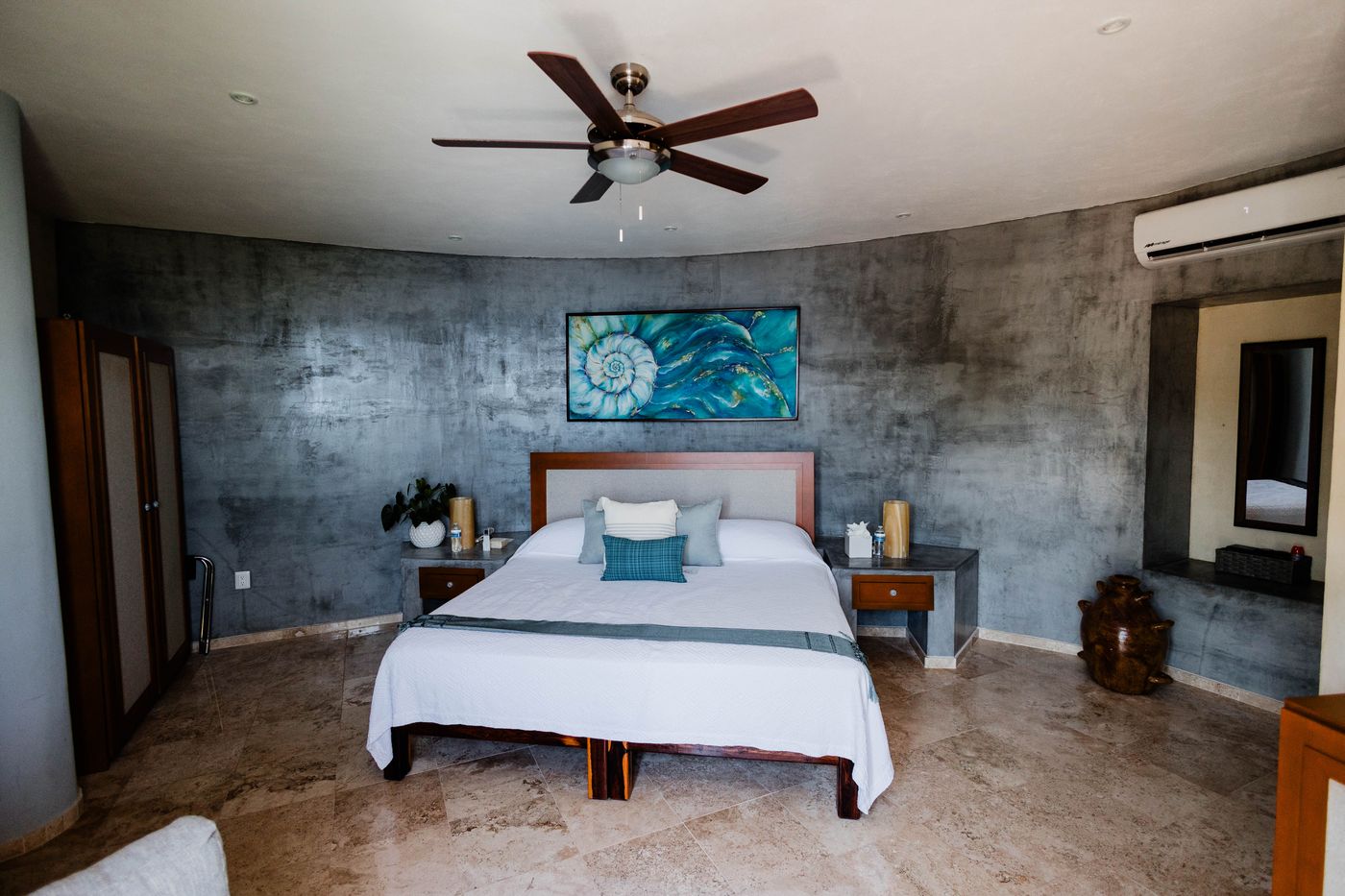 Bedroom with a king bed, concrete walls and a ceiling fan at Villa Mandarinas