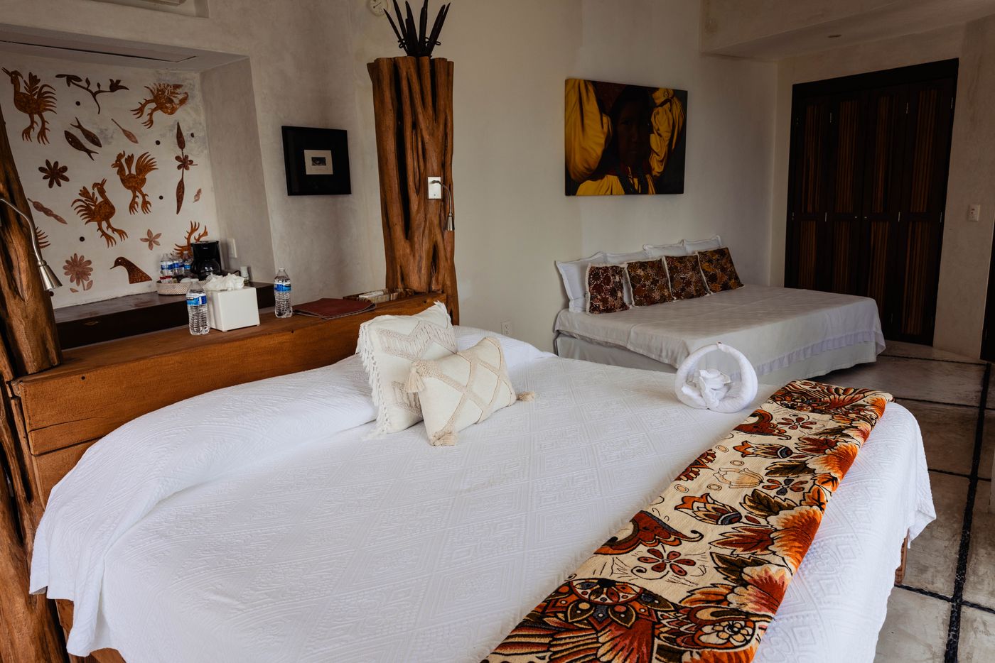 Bedroom with a white bed, patterned throw and wood posts at Villa Mandarinas