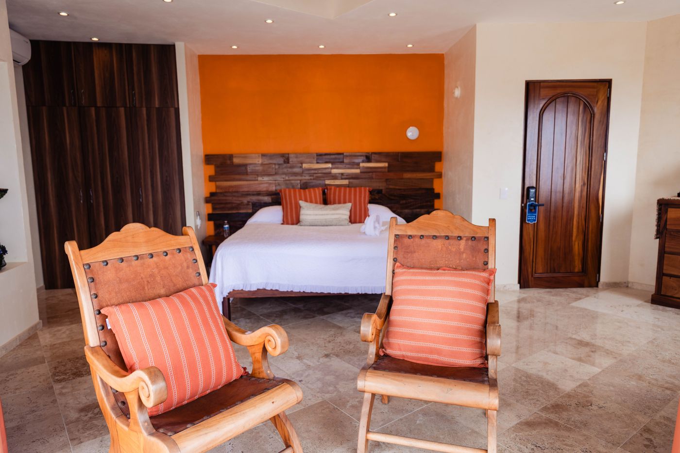 Bedroom with an orange accent wall, wood headboard, bed and two wooden rocking chairs